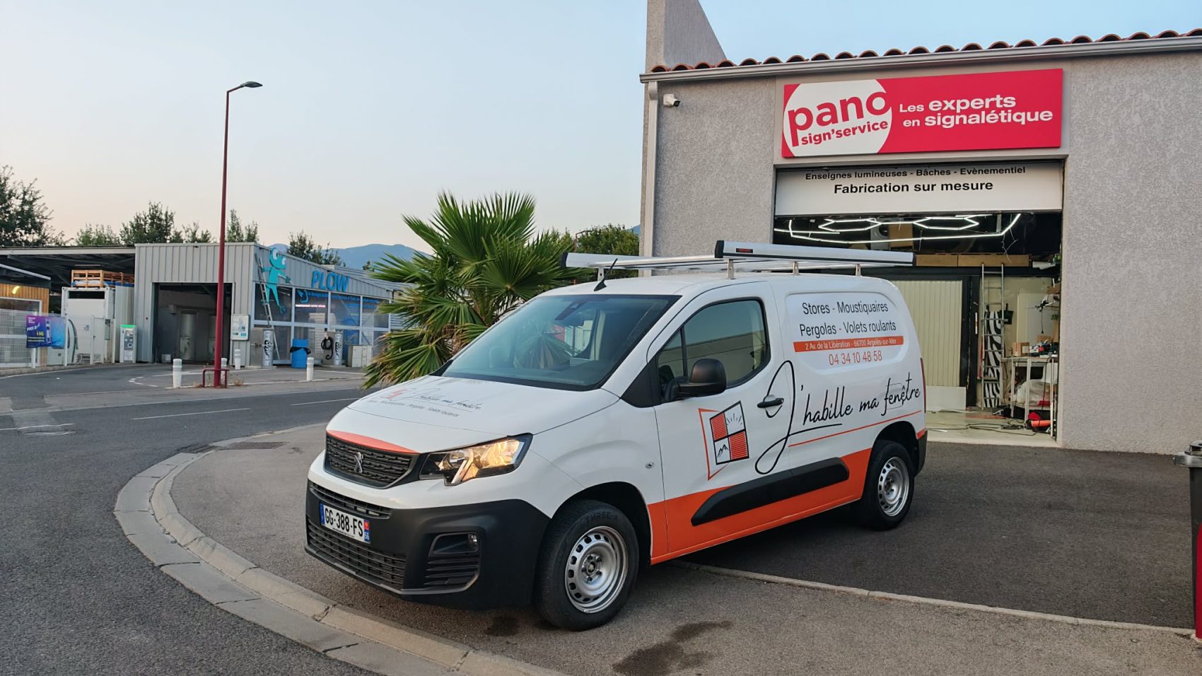 Utilitaire blanc avec lettrage publicitaire et bande rouge, stationné devant l’agence PANO